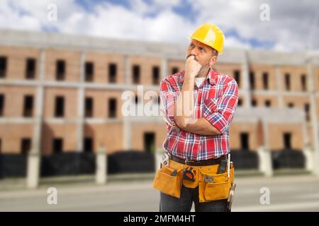 Worker making thinking gesture with hands on chin as looking for solution concept Stock Photo