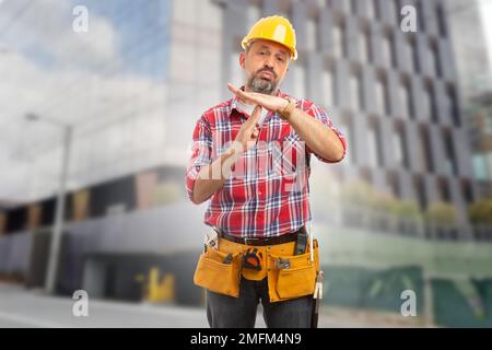 Tired worker making time-out gesture with one hand on top of another and exhausted face expression Stock Photo