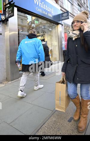 London, England, UK. Woman on her mobile phone inOxford Street on a cold day Stock Photo