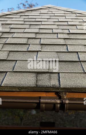 Frosted roof covered with bitumen shingles. The beginning of winter. Stock Photo