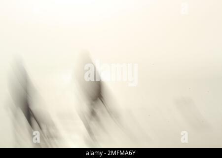 Two abstract shadowy dark figures contrasted against a light background being sucked towards the ground or the earth. Concept for fading away, dying Stock Photo