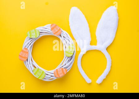 Easter or spring composition with decorative white wreath, wooden eggs and rabbit ears Stock Photo
