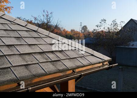 Frosted roof covered with bitumen shingles. The beginning of winter. Stock Photo