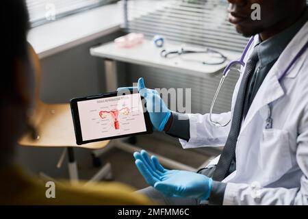 Close up of unrecognizable black doctor holding tablet with female reproductive system chart Stock Photo