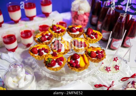 Delicious cakes with berries and other sweets on holiday candy buffet. Lot of tasty desserts on table Stock Photo