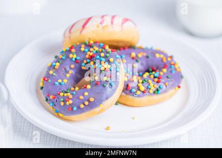 American donuts on white plate on bright background. Playful and colourful image of sweets and desserts. Stock Photo