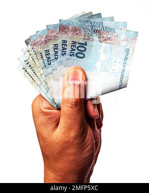 100 reais banknotes of Brazil held by male hand on isolated white background. Stock Photo