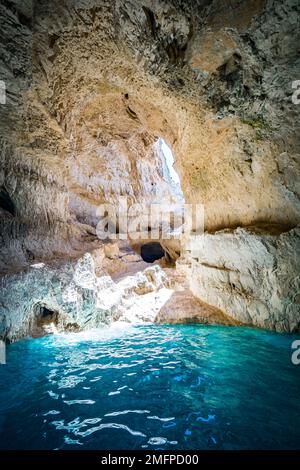 Close-up view of the inside of a sea grotto filled with tropical blue and turquoise water, illuminated by natural sunlight through a small opening Stock Photo