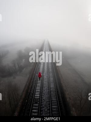 Aerial landscape of railway tracks vanishing into the distance with a suicidal depressed person walking in despair Stock Photo