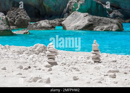 View of cairns, stacks of balanced white round stones, on the beautiful White Beach on Zakynthos, Greece, surrounded by tropical turquoise waters Stock Photo