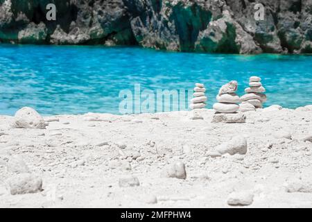 View of cairns, stacks of balanced white round stones, on the beautiful White Beach on Zakynthos, Greece, surrounded by tropical turquoise waters Stock Photo