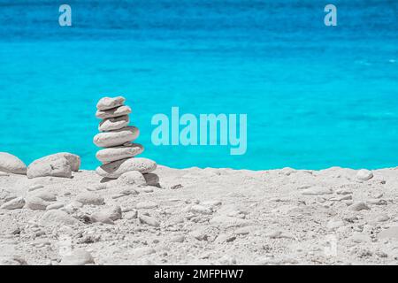 View of a cairn, a stack of balanced white round stones, on the beautiful White Beach on Zakynthos, Greece, surrounded by tropical turquoise waters Stock Photo