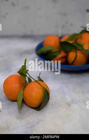Fresh tangerines with green leaves on a light background  Stock Photo