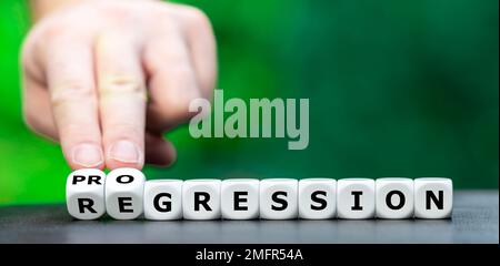 Hand turns dice and changes the word regression to progression. Stock Photo