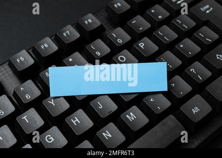 Sticker lying on black keyboard. Important message written over paper. Stock Photo