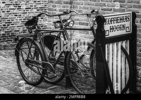 Enkhuizen, Netherlands - August 18,2021: Traditional, Dutch, old bicycles parked near the wall of the coffee house. Black and white photography. Stock Photo