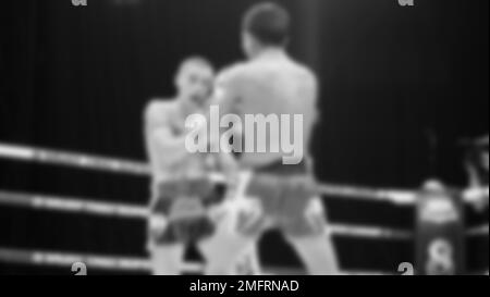 Blurred images black and white photo style of Thai boxing or Muay Thai or Kickboxing which local and foriegn boxer are fighting on the ring at indoor Stock Photo