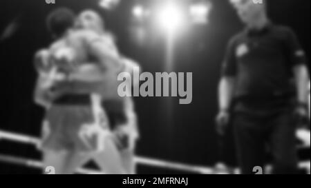 Blurred images black and white photo style of Thai boxing or Muay Thai or Kickboxing which local and foriegn boxer are fighting on the ring at indoor Stock Photo