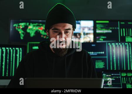 One criminal hacker man programming a phishing virus, at background a lot of data screens. One caucasian developer working on internet firewall system. Cyber security concept. High quality photo Stock Photo