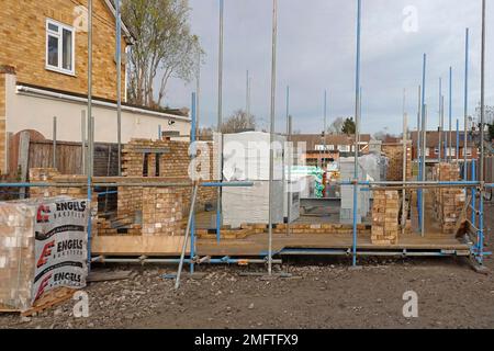 Building materials stacked on house construction site work in progress on external detached house cavity walls of facing bricks & insulating blocks UK Stock Photo