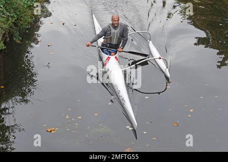 Aerial view male canoeist paddling in Italian Allwave Vanguard outrigger canoe along still waters of River Can in City of Chelmsford Essex England UK Stock Photo