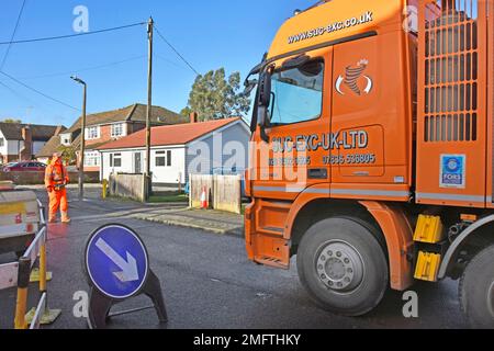 Hgv lorry truck driver in residential street slowly moving large suction excavation machine by remote control for gas main replacement work England UK Stock Photo