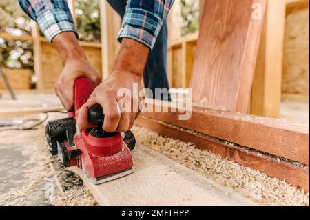 construction worker sanding down wood piece Stock Photo