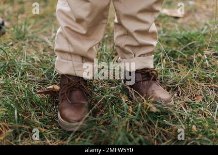 cropped photo of kids legs in leather brown shoes and beige pants outdoors at autumn park with maple leaves children adventure on fresh air internati 2mfw5y0