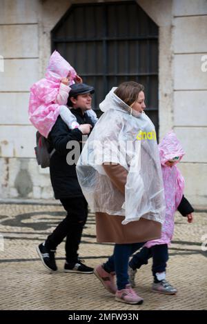 Family of tourists sheltered from the rain with raincoats Stock Photo