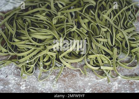 Fresh pasta. Homemade italian raw fettuccine pasta with spinach on wooden table background. High quality photo Stock Photo
