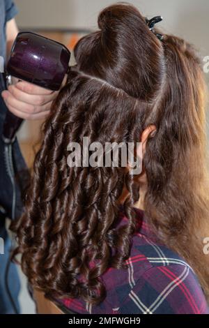 Woman hairdresser makes the wedding or evening curly hairstyle using spray  lacquer fix Stock Photo - Alamy