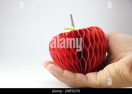 Paper apple with 3d effect made from color paper held in hand with space for copy text Stock Photo