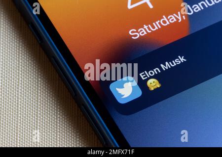 Notification of a new tweet from Elon Musk with a hugging face emoji is seen on the lock screen of an iPhone. Elon Musk's Twitter takeover concept. Stock Photo