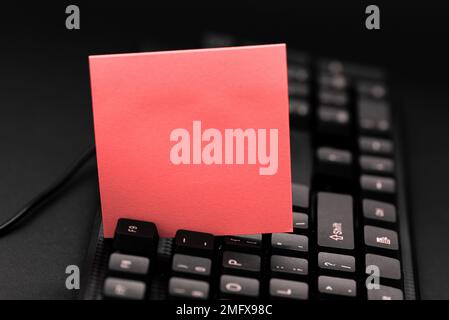 Colored sticker lying on keyboard. Important message written over paper. Stock Photo