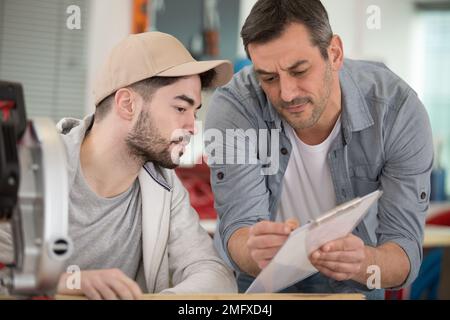 supervisor in discussion with apprentice looking at clipboard Stock Photo