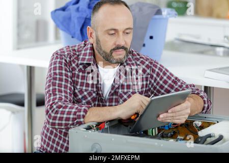 serviceman using tablet to diagnose and repair appliance Stock Photo