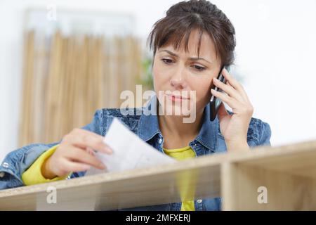 arpenter discussing order details with her customer on smartphone Stock Photo