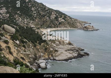 Hilly landscape just outside Phan Rang Vietnam, with cloudy skies on a partially sunny day with the mountains sloping down to the sea Stock Photo