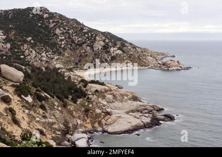 Hilly landscape just outside Phan Rang Vietnam, with cloudy skies on a partially sunny day with the mountains sloping down to the sea Stock Photo