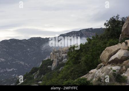 Hilly landscape just outside Phan Rang Vietnam, with cloudy skies on a partially sunny day with the mountains sloping down to the sea Stock Photo