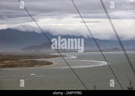 Hilly landscape just outside Phan Rang Vietnam, with cloudy skies on a partially sunny day with the mountains sloping down to the sea Stock Photo