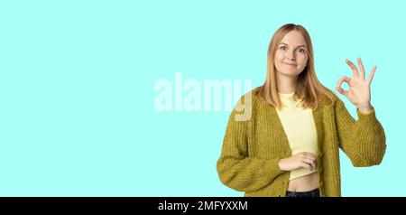 Beautiful blonde woman smiling happy doing ok sign with hand on eye looking through fingers  Stock Photo