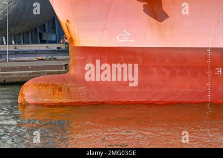 Close up view of the bulbous bow of a large cargo ship with painted markings on the side to indicate its depth in the water. No people. Stock Photo