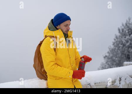 European man stopped in snowy place to drink tea from thermos to breathe fresh frosty air in nature. Stock Photo