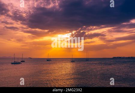 Sun is starting to set behind clouds. View from the Promenade near Marina Rubicon in Playa Blanca, Lanzarote. Stock Photo