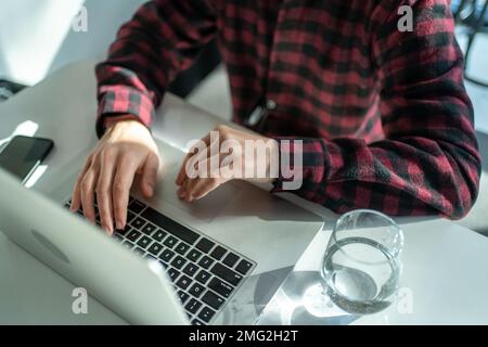 Freelancer working on laptop in cafe, close-up on hands and laptop keyboard, top view. Stock Photo