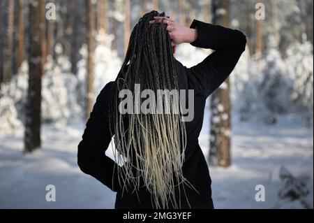 Woman with long African braids in winter landscape in the forest Stock Photo