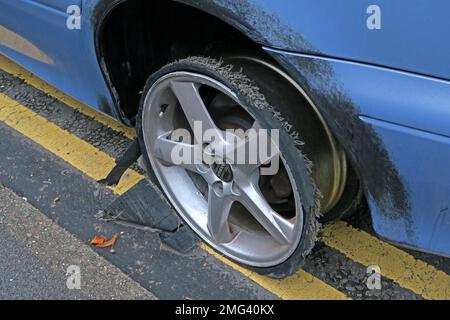 Front car tyre shredded at speed, stopped on double yellow lines, Cheshire, England, UK - Flat low profile tyre on alloy rim, ripped open Stock Photo