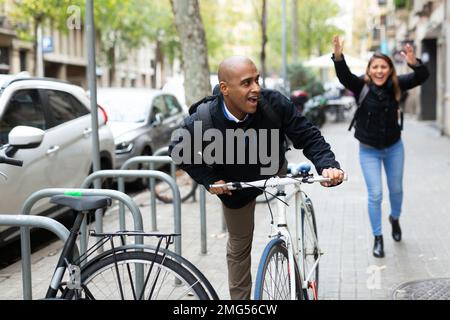 Man stealing bicycle, woman owner running after Stock Photo