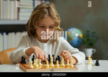 Pupil kid thinking about his next move in a game of chess. Concentrated  little boy sitting at the table and playing chess Stock Photo - Alamy